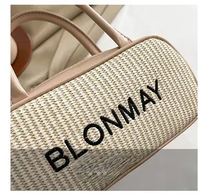 Macro shot of embroidered logo on a beige woven tote bag with premium leather trim