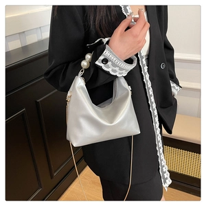 Detail of pearlescent silver handbag with large pearl handle and metal chain strap