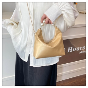 Detail of elegant pearl handle on beige crescent bag with smooth glossy finish
