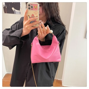 Pink leather handbag detail featuring large faux pearl handle and elegant finish