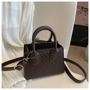 Detail of dark brown mini tote bag featuring woven texture and gold hardware adjustments