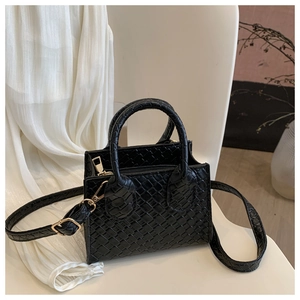 Macro detail of black woven PU leather texture and gold metal zipper on small square bag