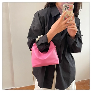Pink Hobo bag featuring a large pearl handle and metal chain strap in a mirror selfie