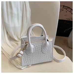 Close-up of white crossbody bag with woven texture, round handles and gold hardware