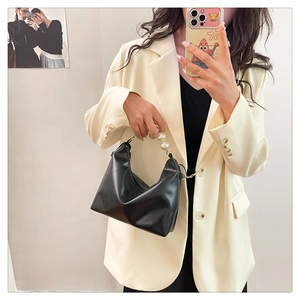 Detail of elegant black faux leather handbag with white pearl beaded top handle