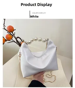 Detail of white leather crossbody bag featuring pearl bead handle and gold chain strap