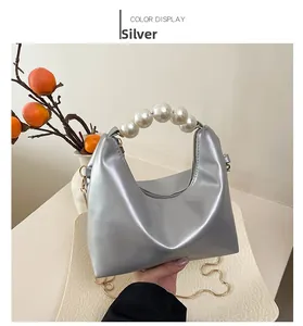 Silver pillow handbag featuring oversized pearl handle and delicate gold chain strap