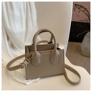 Detail of mini square crossbody bag with woven texture, top handles and gold buckle strap