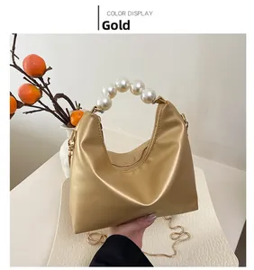 Detailed view of the gold hobo bag featuring a pearl handle and chic metal chain strap