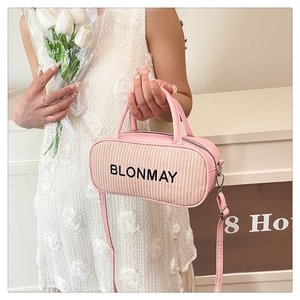 Pink cylinder bowling bag with woven texture and leather trim shown in a lifestyle setting