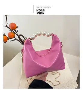 Detail of rose pink handbag featuring elegant pearl handle and gold chain strap