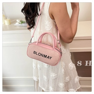 Detail of pink woven bowling bag with black BLONMAY logo worn by model in white dress