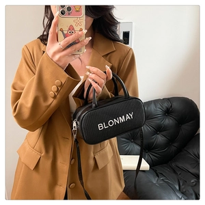 Mirror selfie showing a black woven baguette bag with adjustable shoulder strap