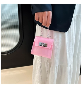 Detalle de mini bolso jelly rosa con cierre plateado y cadena sobre una falda blanca