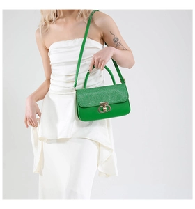 Detail of green sequin handbag with gold ring lock shown on model for size perspective