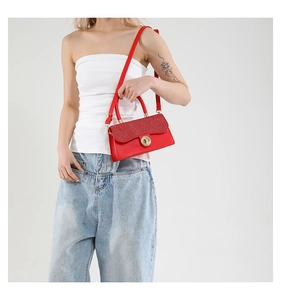 Close-up of red leather handbag featuring glitter flap and gold circular twist lock