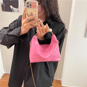 Chic pink semi-circle handbag featuring a large pearl handle and gold chain strap