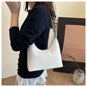 Close-up of white minimalist hobo bag with smooth texture and adjustable shoulder strap