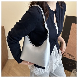 Close-up of a silver metallic hobo bag with adjustable strap worn by a model