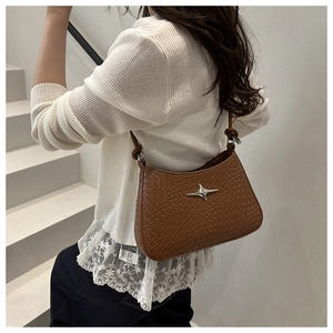 Close-up of woven texture shoulder bag featuring a silver star emblem and knotted strap