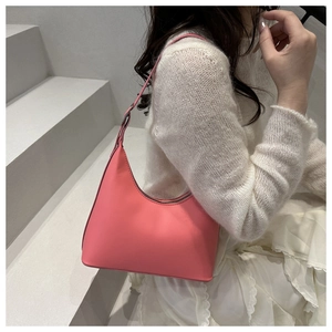 Minimalist pink leather crescent bag styled with a white knit outfit on a grey staircase