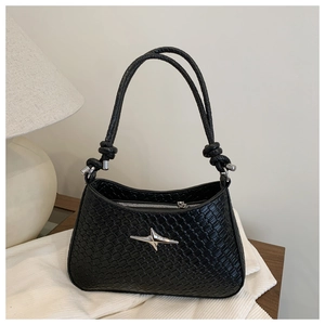 Detail of black woven shoulder bag featuring silver star emblem and knotted handle