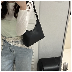 Detailed close-up of a black minimalist hobo bag with silver zipper and smooth texture