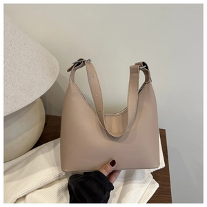 Detail of a beige leather hobo bag with adjustable strap on a wooden table setup