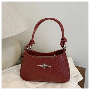 Detail of dark red faux snakeskin handbag with star logo and knotted handle design