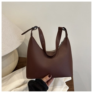 Close-up of a dark brown matte leather baguette bag with silver zipper and adjustable strap