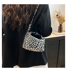 Close-up of leopard print crossbody bag with silver hardware on a female model