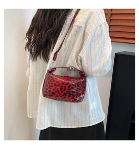 Detail of red and black leopard print crossbody bag featuring glossy patent leather finish