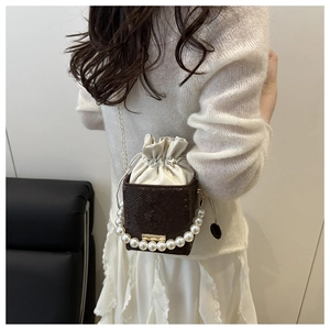 Detail of snake skin crossbody bag featuring a large pearl handle and drawstring closure