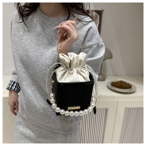 Detail of black snake-textured bucket bag with pearl handle and white drawstring closure