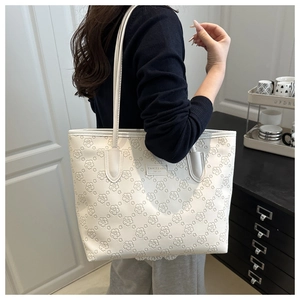 Détail d'un sac cabas blanc en similicuir avec motifs floraux gaufrés et fines lanières