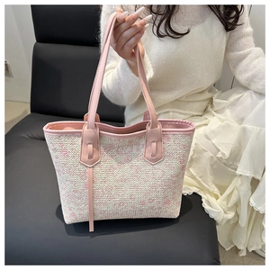 Detail of pink faux leather handles and floral woven texture on a large beach tote bag