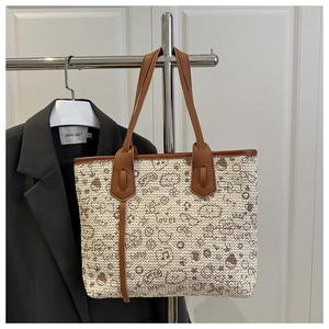 Close-up of woven tote bag featuring cute cartoon graffiti and brown leather handles