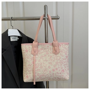Detail of pink woven large tote bag with leather handles shown in a minimal studio setting