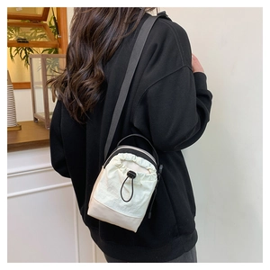 Detail of a beige drawstring crossbody bag with adjustable strap worn by a model