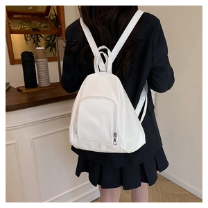Rear view of a white minimalist backpack worn by a model in a cozy cafe setting