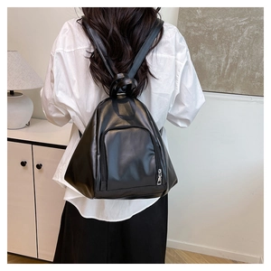 Detail of a minimalist black PU leather backpack showing silver zippers and slim straps