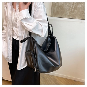 Detailed side view of black shiny PU leather hobo tote bag worn by a model for daily use