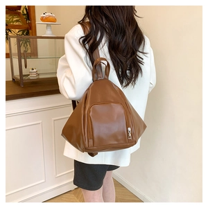 Rear view of a model wearing the brown leather triangle backpack in a cozy indoor setting