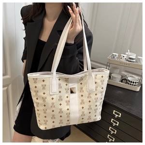 Close-up of cream tote bag with bear print pattern and signature metal logo plate