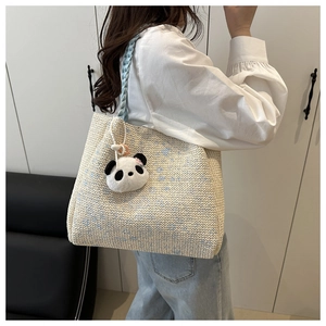 Detailed texture of ivory woven tote bag with blue polka dots and a panda charm