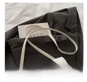 Details der weißen Satteltasche aus Leder mit verstellbarem Riemen und goldenem Schriftzug