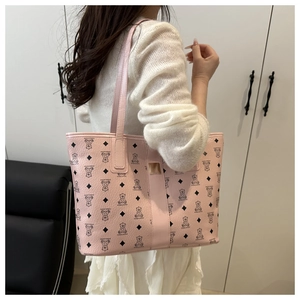 Detail of pink tote bag with bear pattern, leather texture, and golden buckle