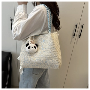 Close-up of woven tote bag featuring blue and white texture with panda charm detail
