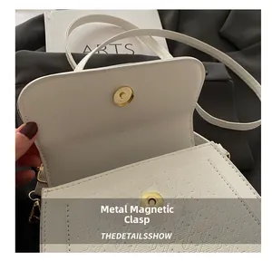 Detail des goldenen Magnetverschlusses an der weißen PU-Leder Tasche mit Hahnentrittmuster