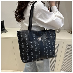 Detailed view of black tote bag featuring cartoon bear patterns and lychee leather texture